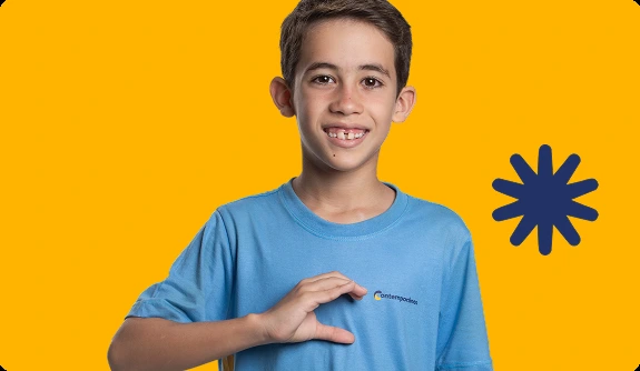 Aluno do Contemporâneo sorrindo, em frente a fundo amarelo com grafismo de asterisco