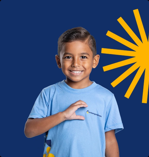 Aluno do Contemporâneo sorrindo, com a mão no peito sobre o uniforme, em frente a fundo azul-marinho com grafismo do sol