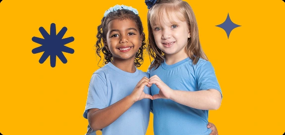 Duas alunas do Contemporâneo abraçadas, fazendo coração com as mãos, em frente a fundo amarelo com grafismo de asterisco e sparkle